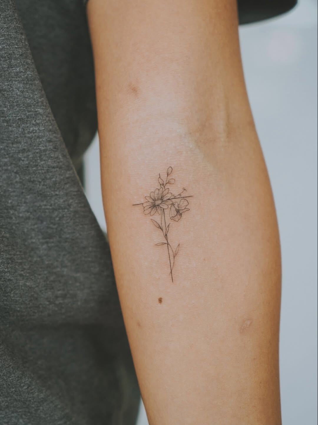 Delicate fine-line floral tattoo with slender stem