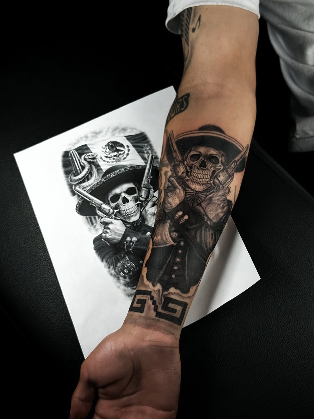 Bold black-and-gray skull charro with pistols, dramatic shading