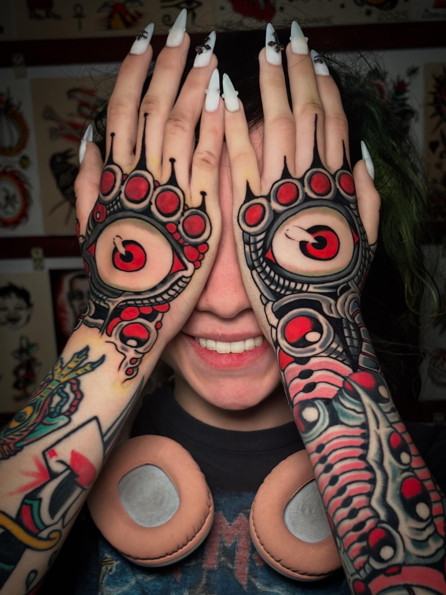 Bold freehand blackwork with red circular motifs across hands