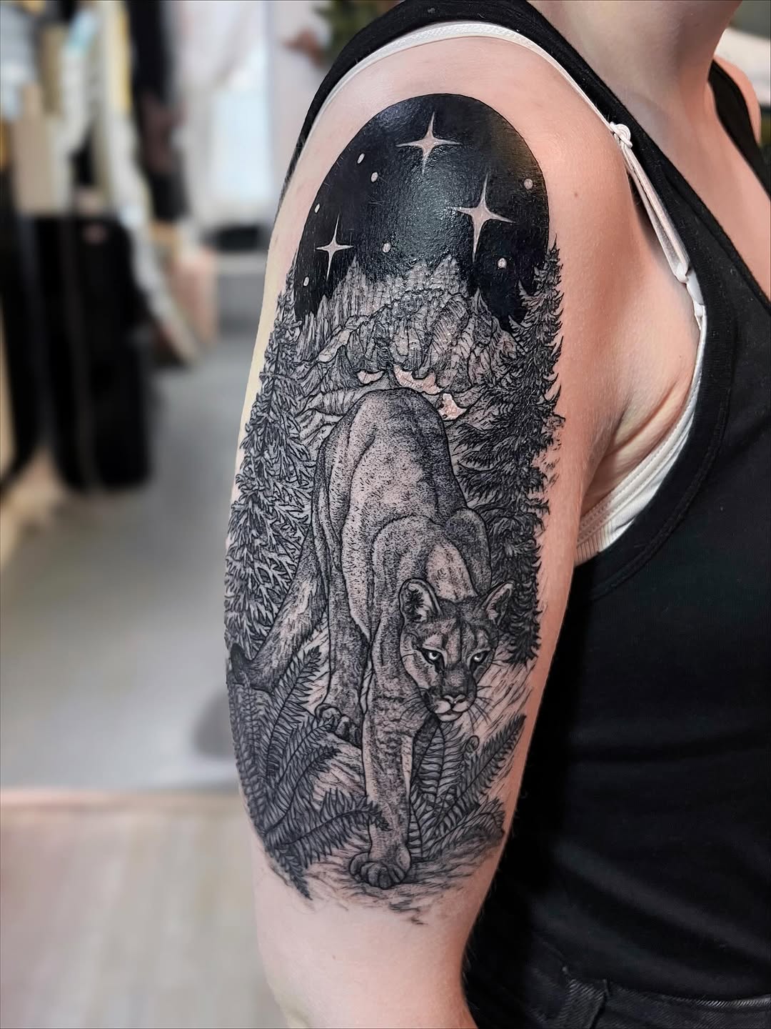 Bold black-and-gray mountain lion stalking through forest at night.