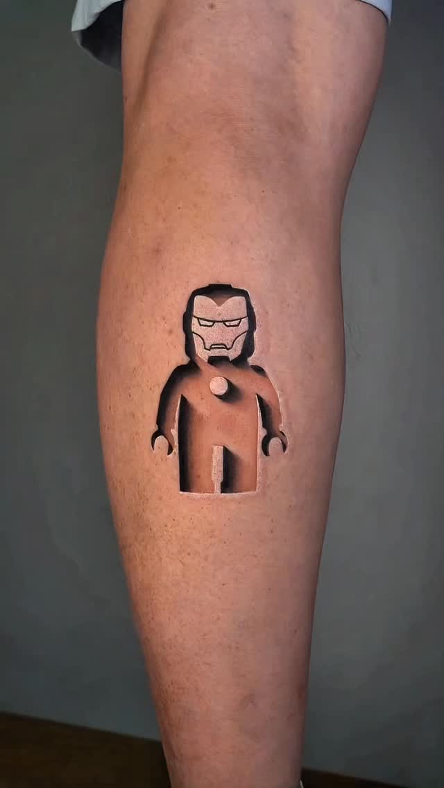 Negative-space LEGO Iron Man silhouette on calf