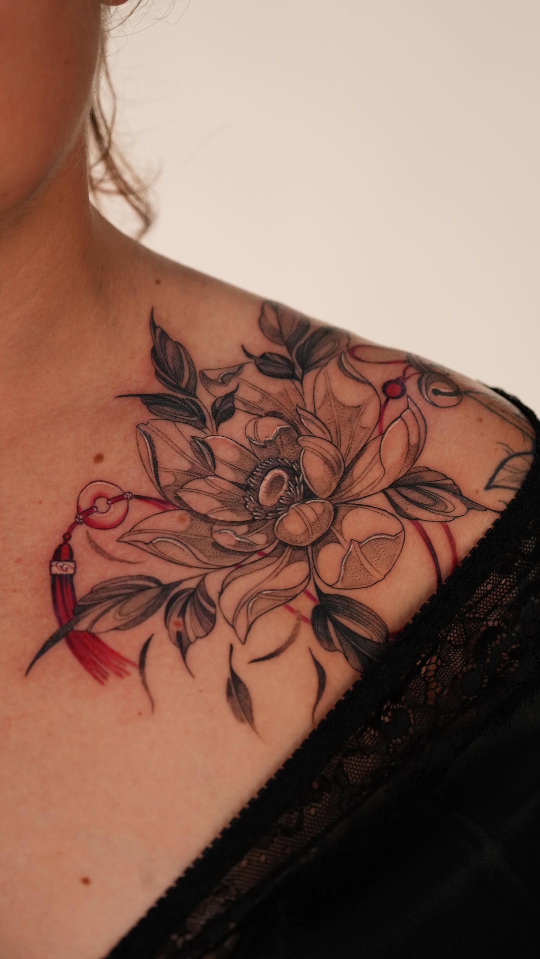 Delicate botanical collarbone piece in fine-line blackwork with red accents