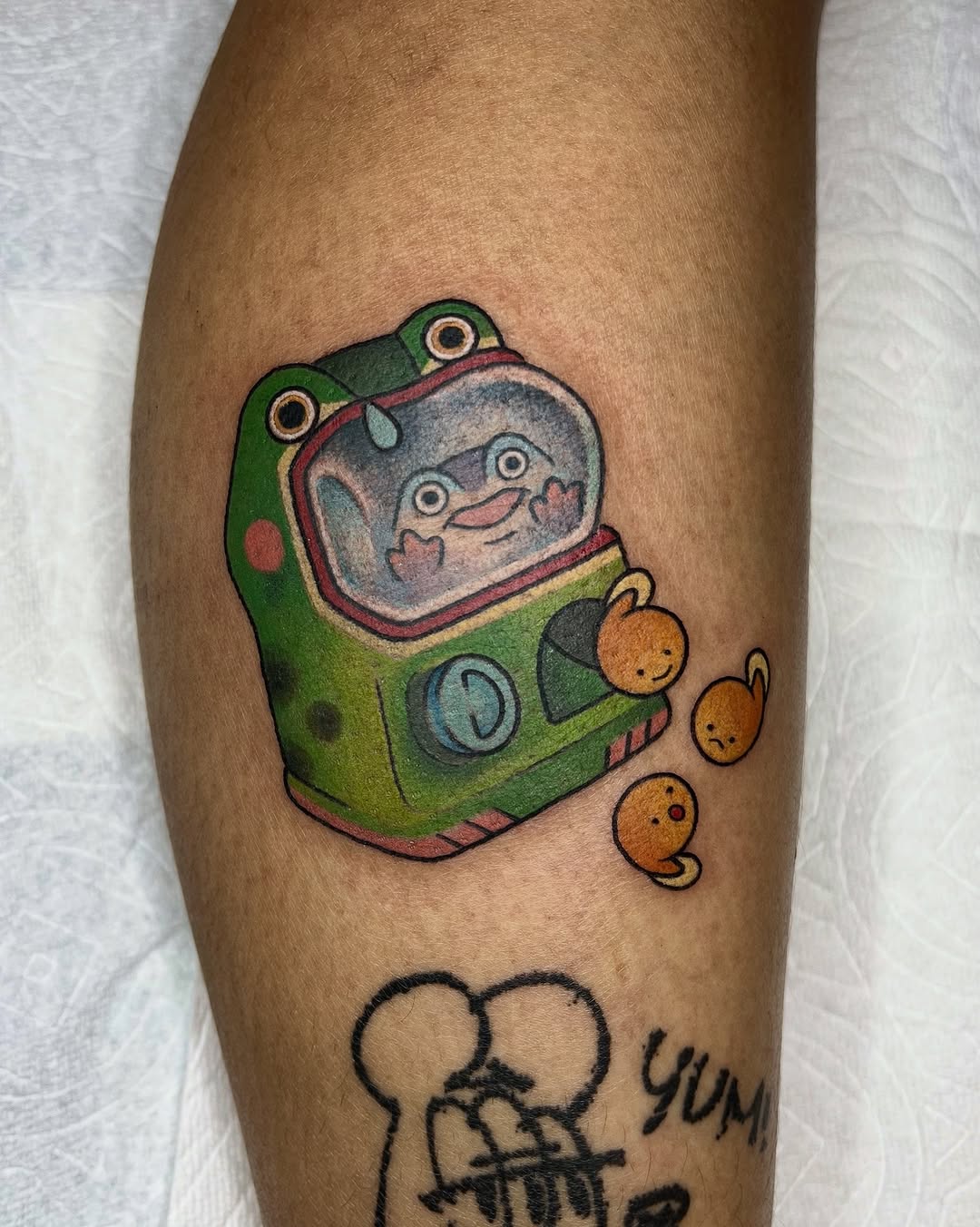 Whimsical green-helmet space frog with orange buddy aliens.