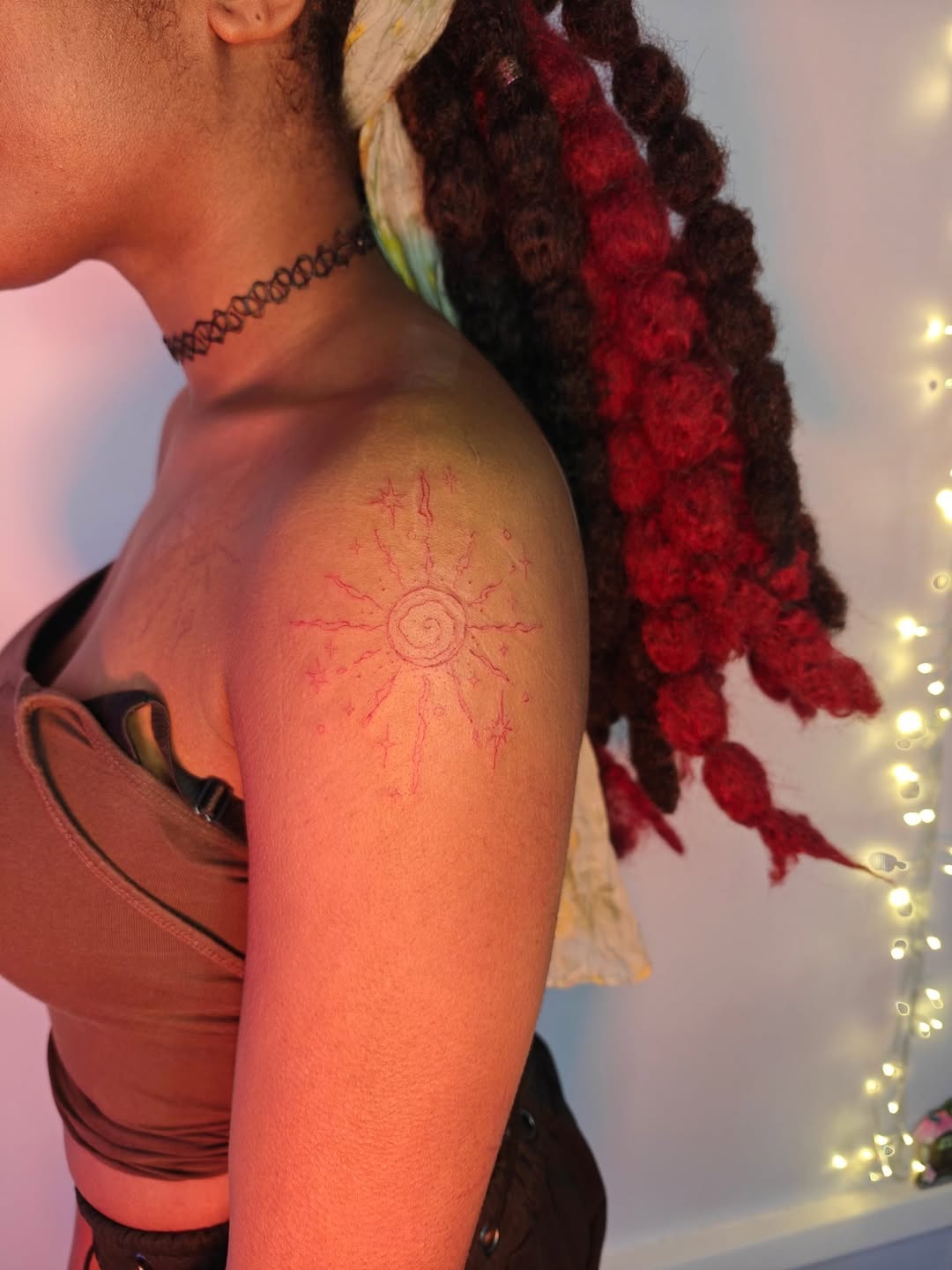 Delicate red sunburst on shoulder with radiant fine lines.