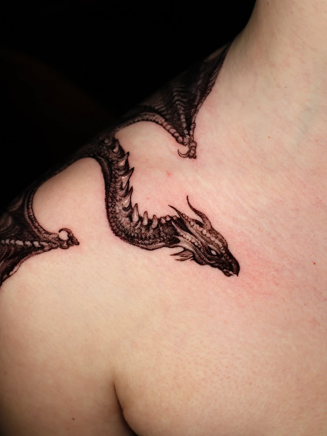 Intricate black dragon with bold linework along shoulder