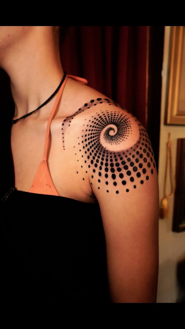Intricate dotwork spiral radiating across the shoulder
