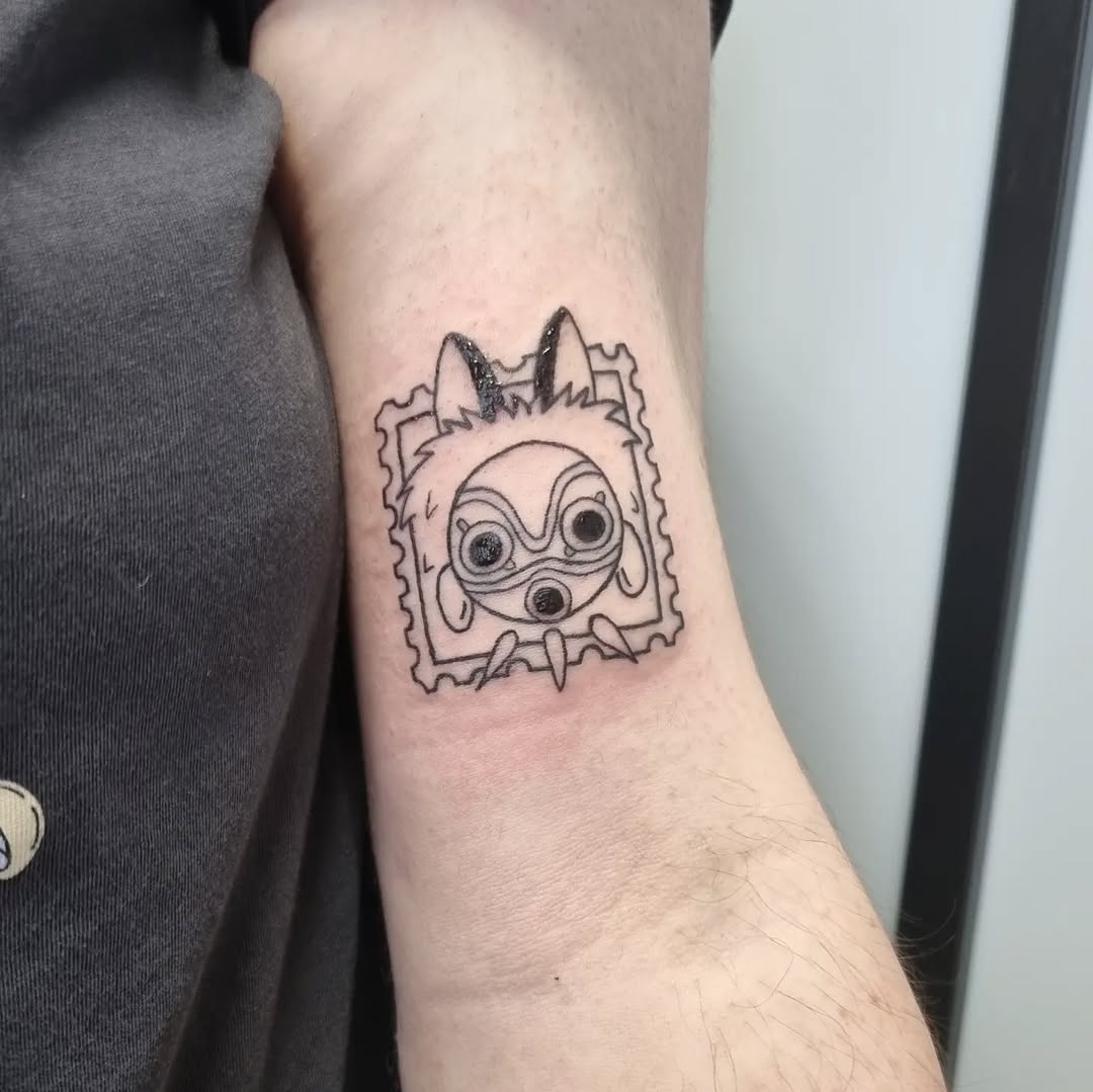 Cute stamp-style animal mask tattoo on inner forearm.