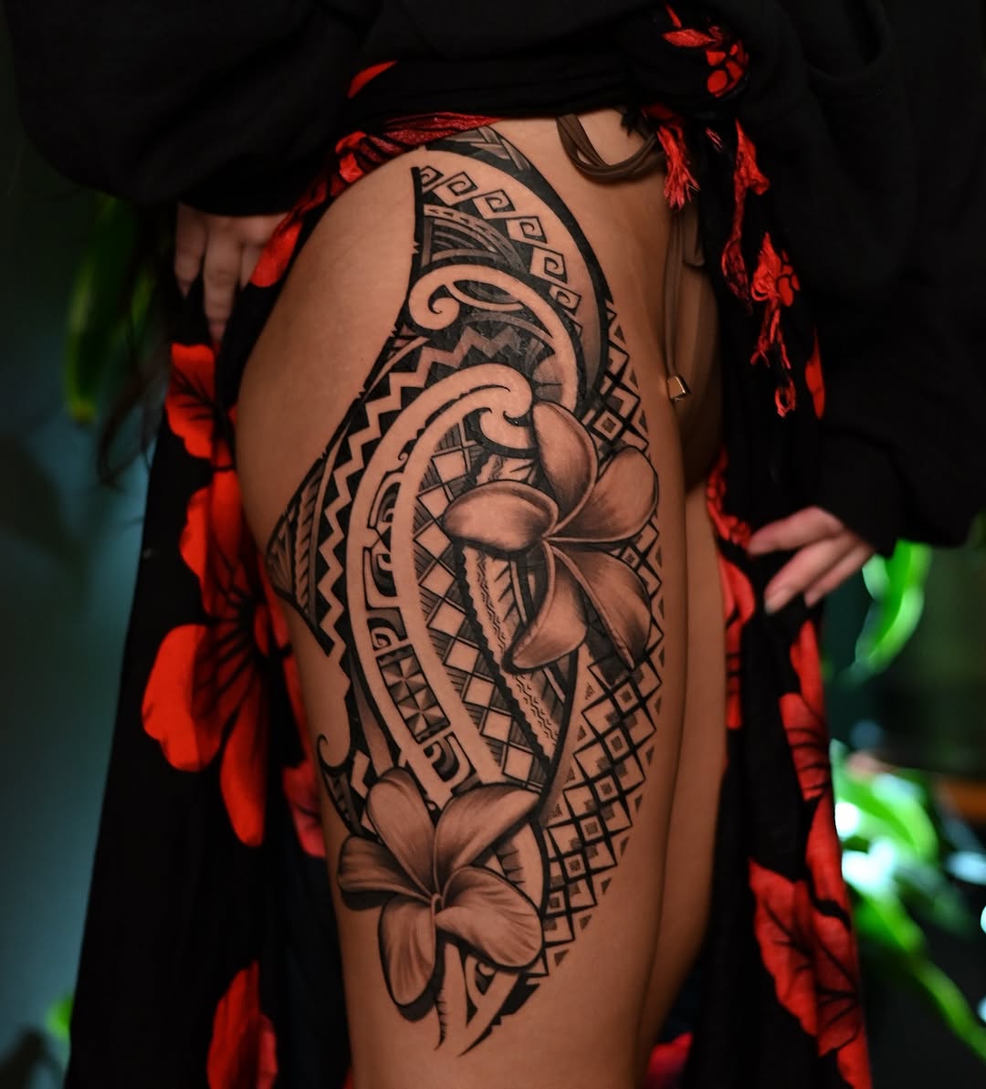 Intricate blackwork thigh piece with geometric motifs and plumeria flowers