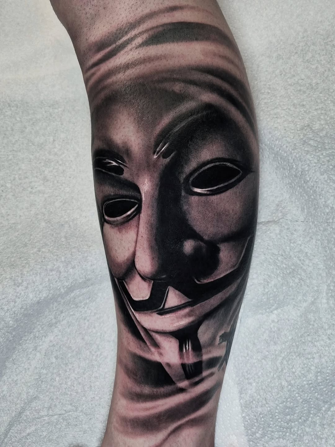 Hyper-realistic grayscale Guy Fawkes mask on calf