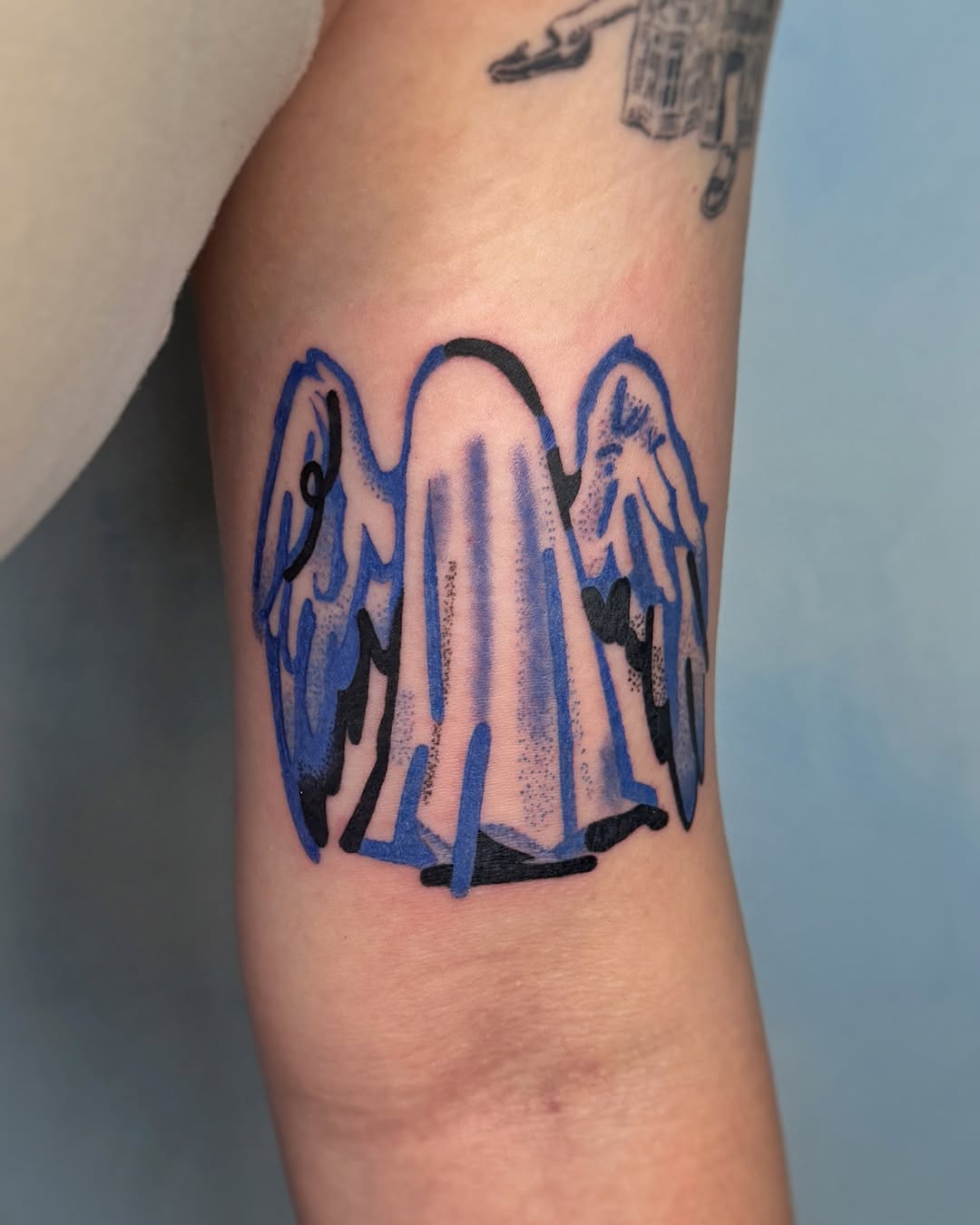 Stylized standing angel with blue wings, bold linework.