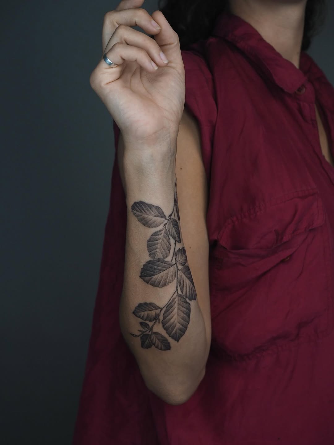 Delicate black-and-gray vine of leaves along forearm