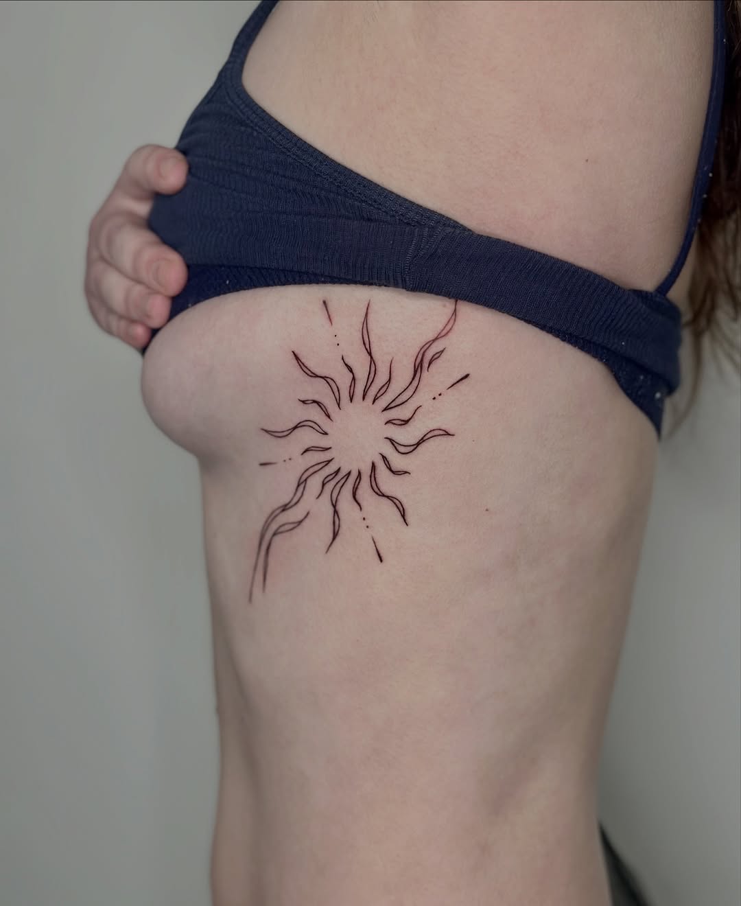 Delicate sunburst linework tattoo with wavy rays