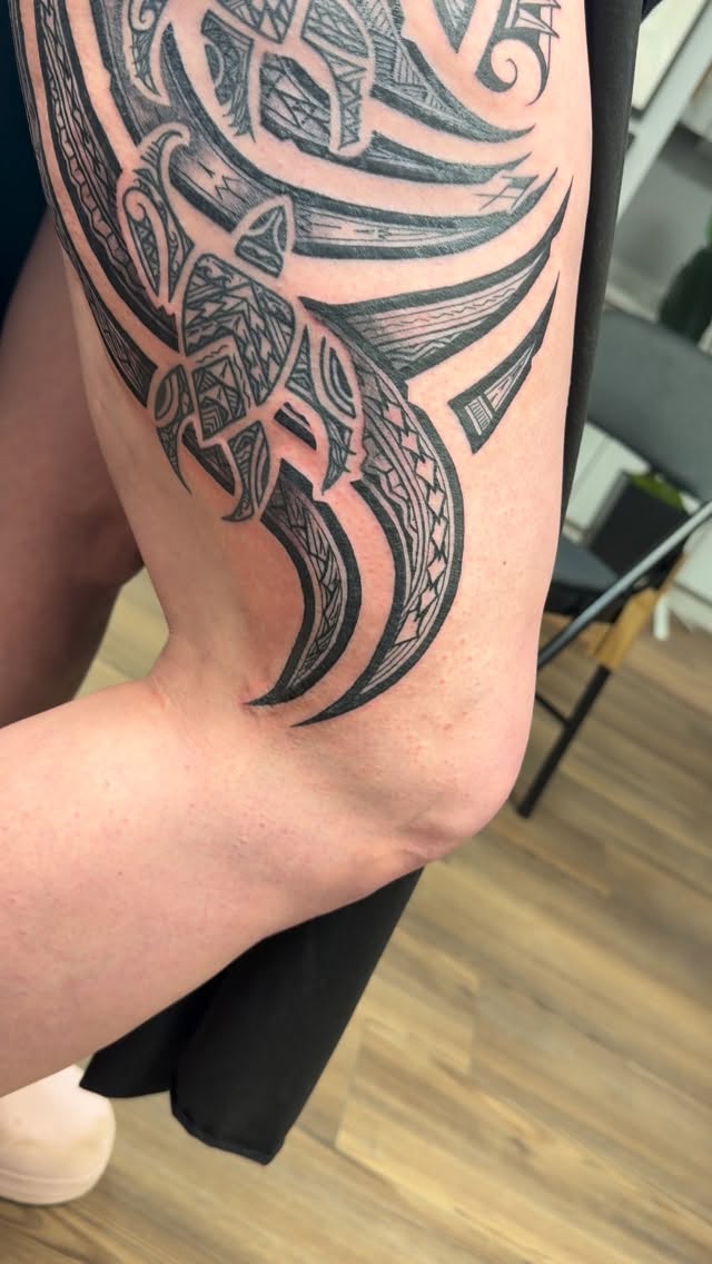 Bold Polynesian blackwork leg tattoo with intricate curves