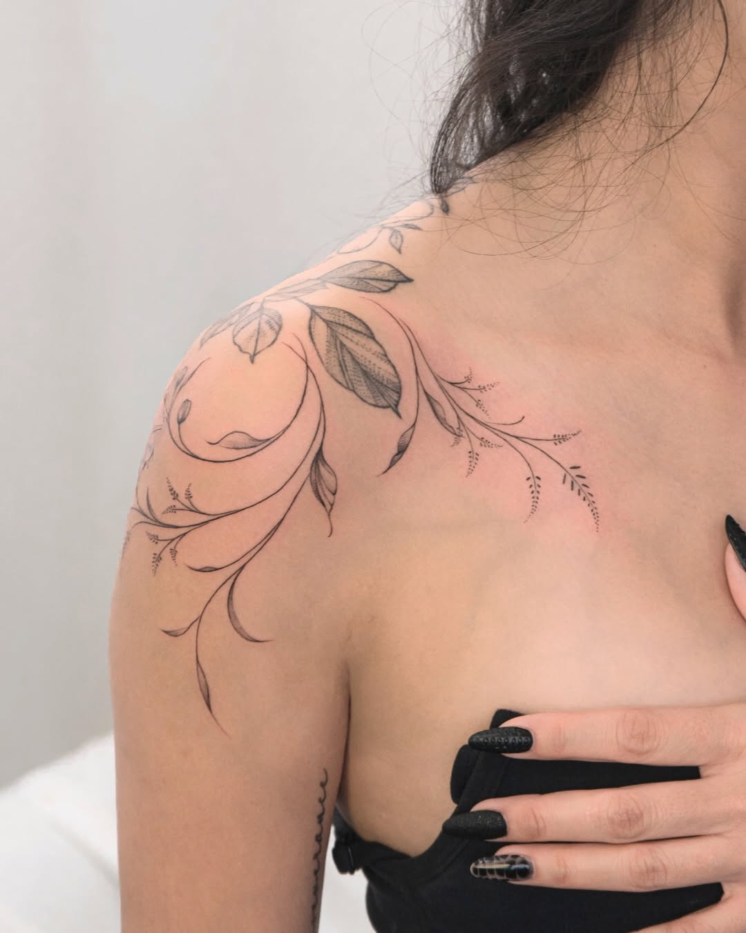 Delicate botanical shoulder vines in fine-line style.