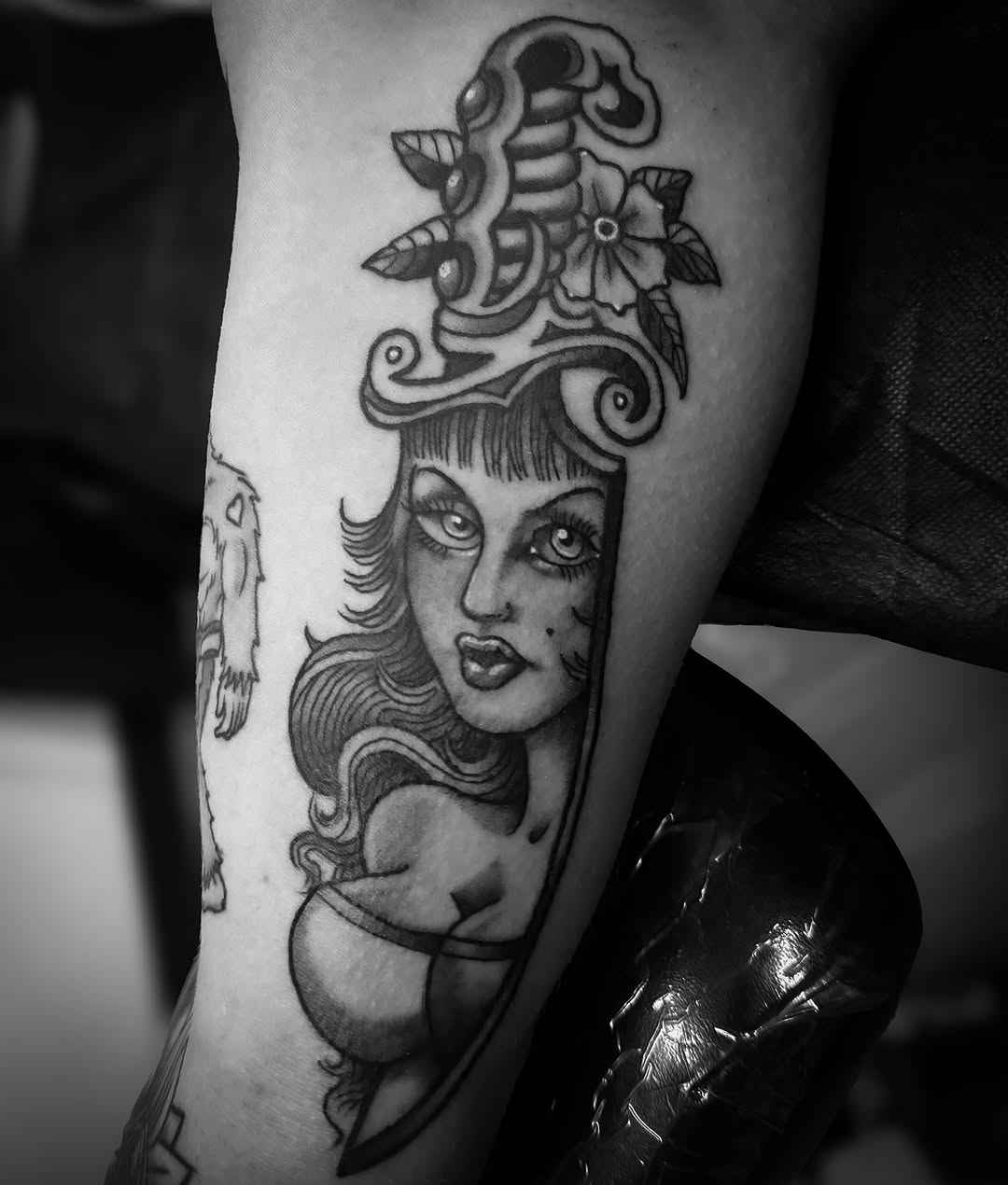 Bold black-and-gray pin-up portrait with ornate scrollwork