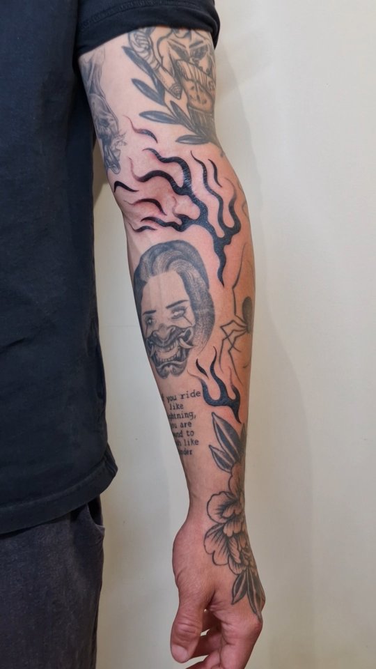 Bold blackwork flames frame a haunting circular mask.