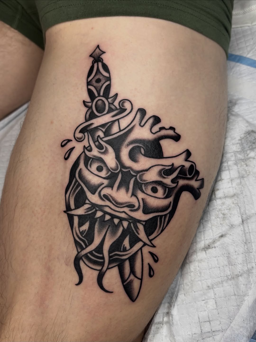 Bold blackwork demon mask with dagger-embedded sword