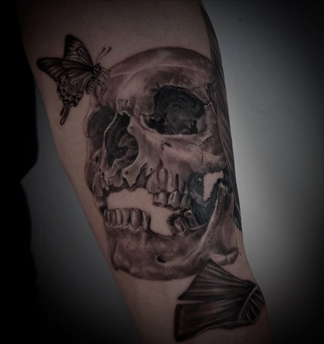 Dark black-and-gray skull with a delicate butterfly