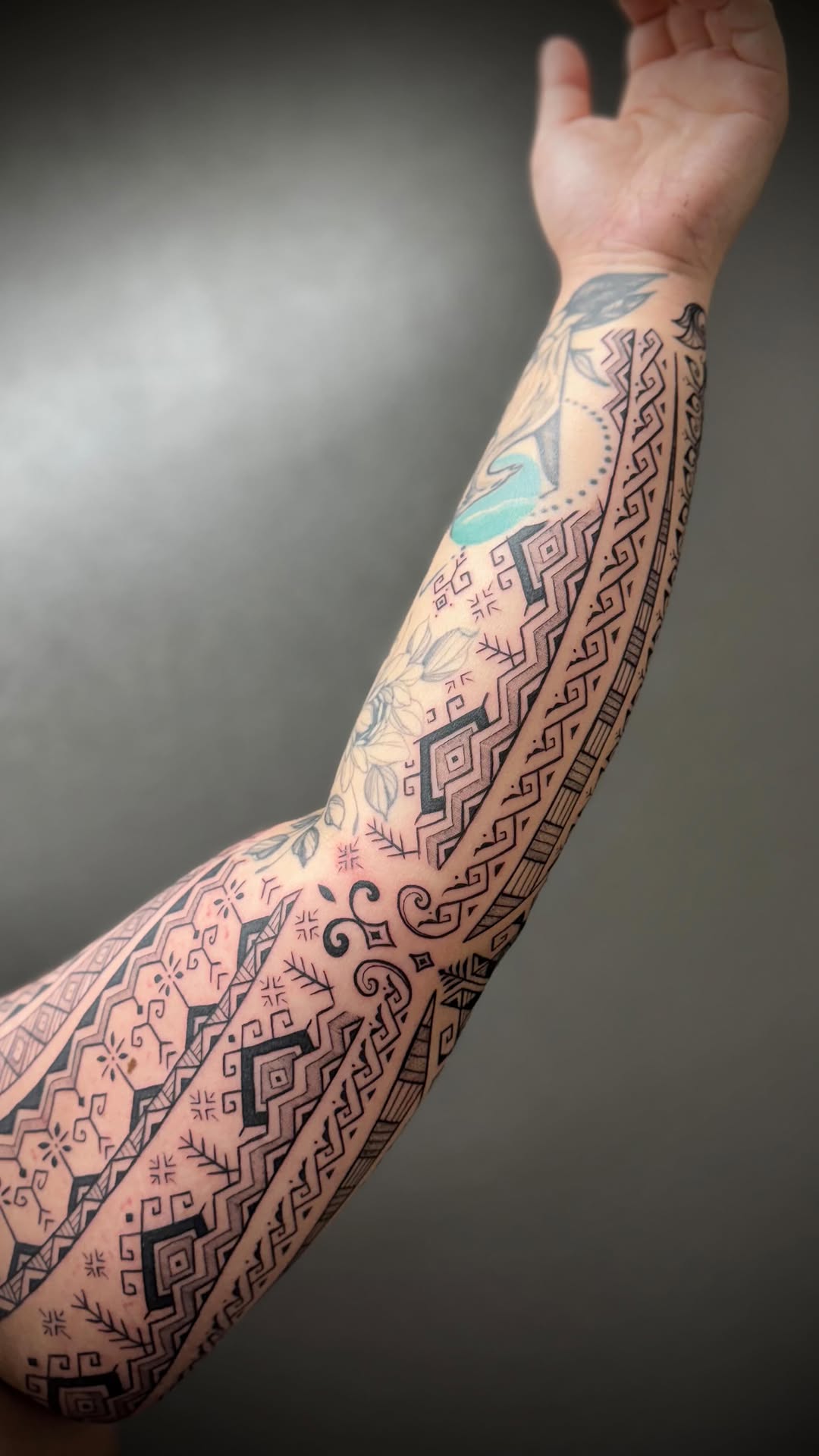 Intricate geometric blackwork forearm sleeve with delicate floral accents