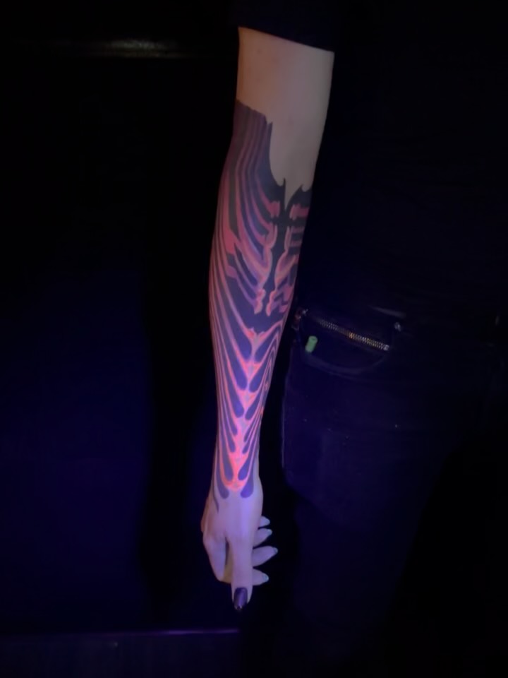 Neon UV-reactive geometric forearm sleeve with flowing organic shapes