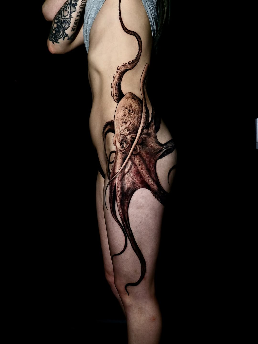 Immense black-and-gray octopus wraps torso with sinewy tentacles