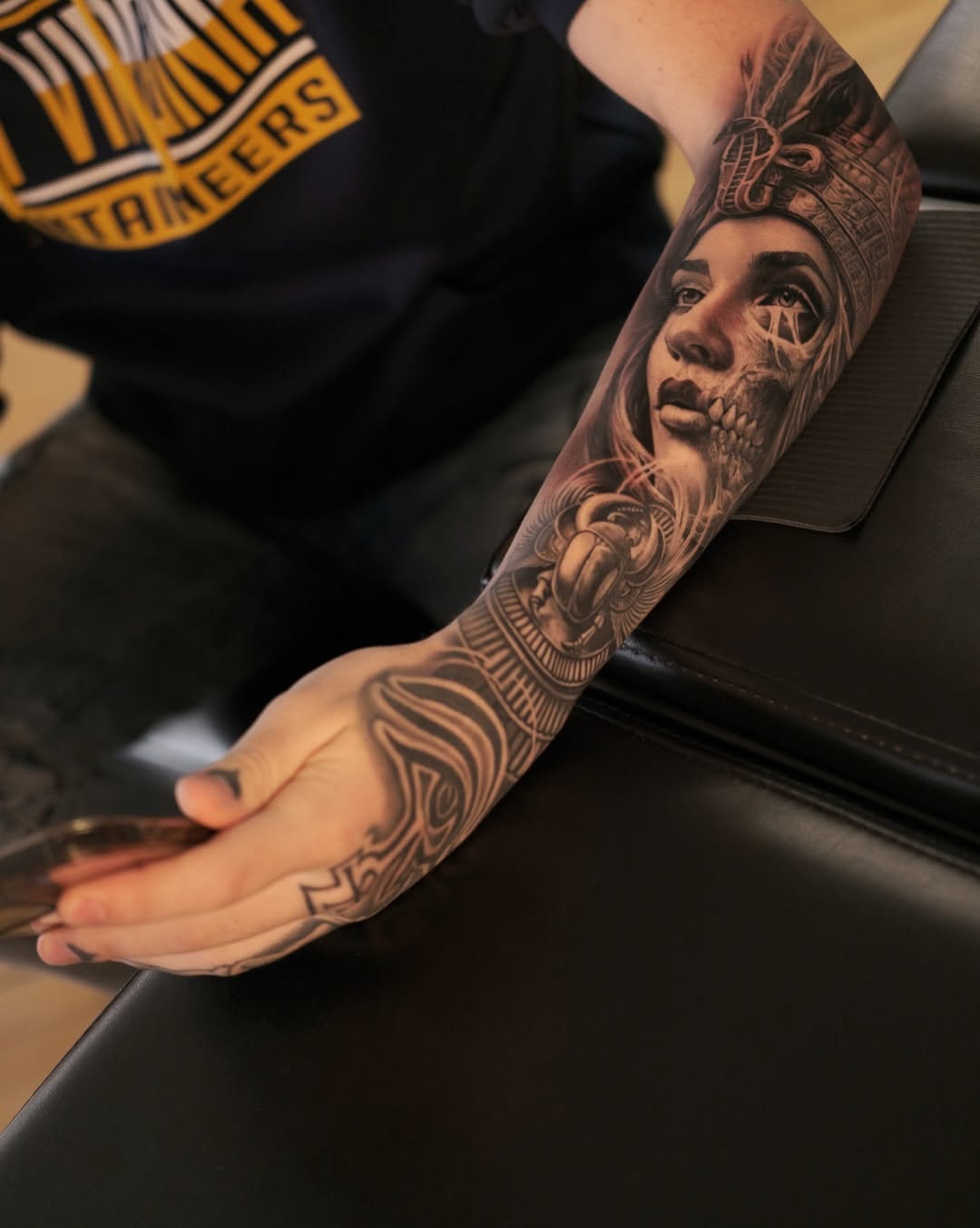 Hyper-detailed black-and-gray forearm sleeve with portrait and skullwork