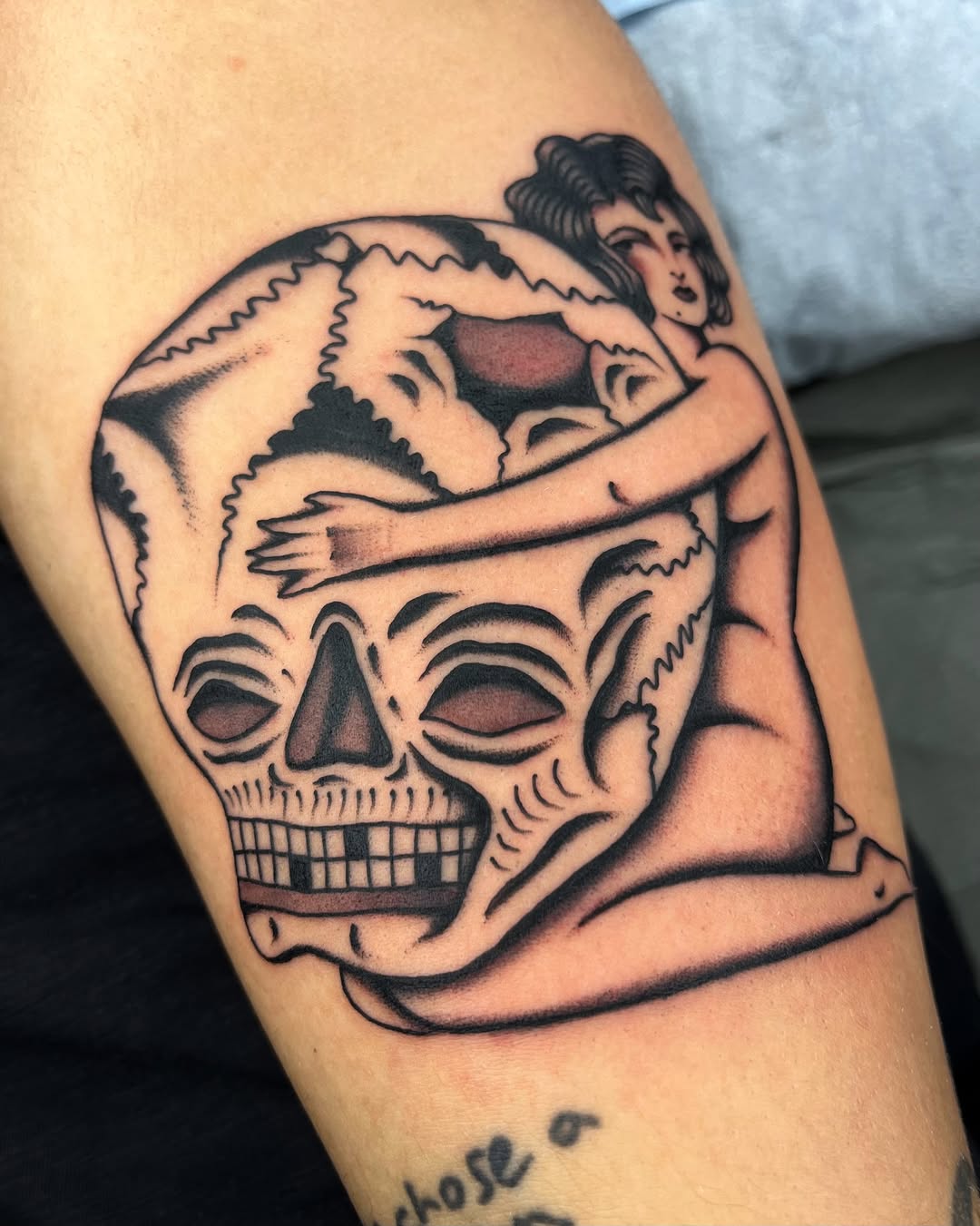 Bold traditional skull embraces a vintage femme figure