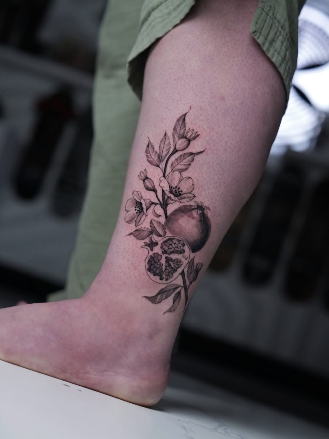 Delicate pomegranate blossom branch with fruit on ankle