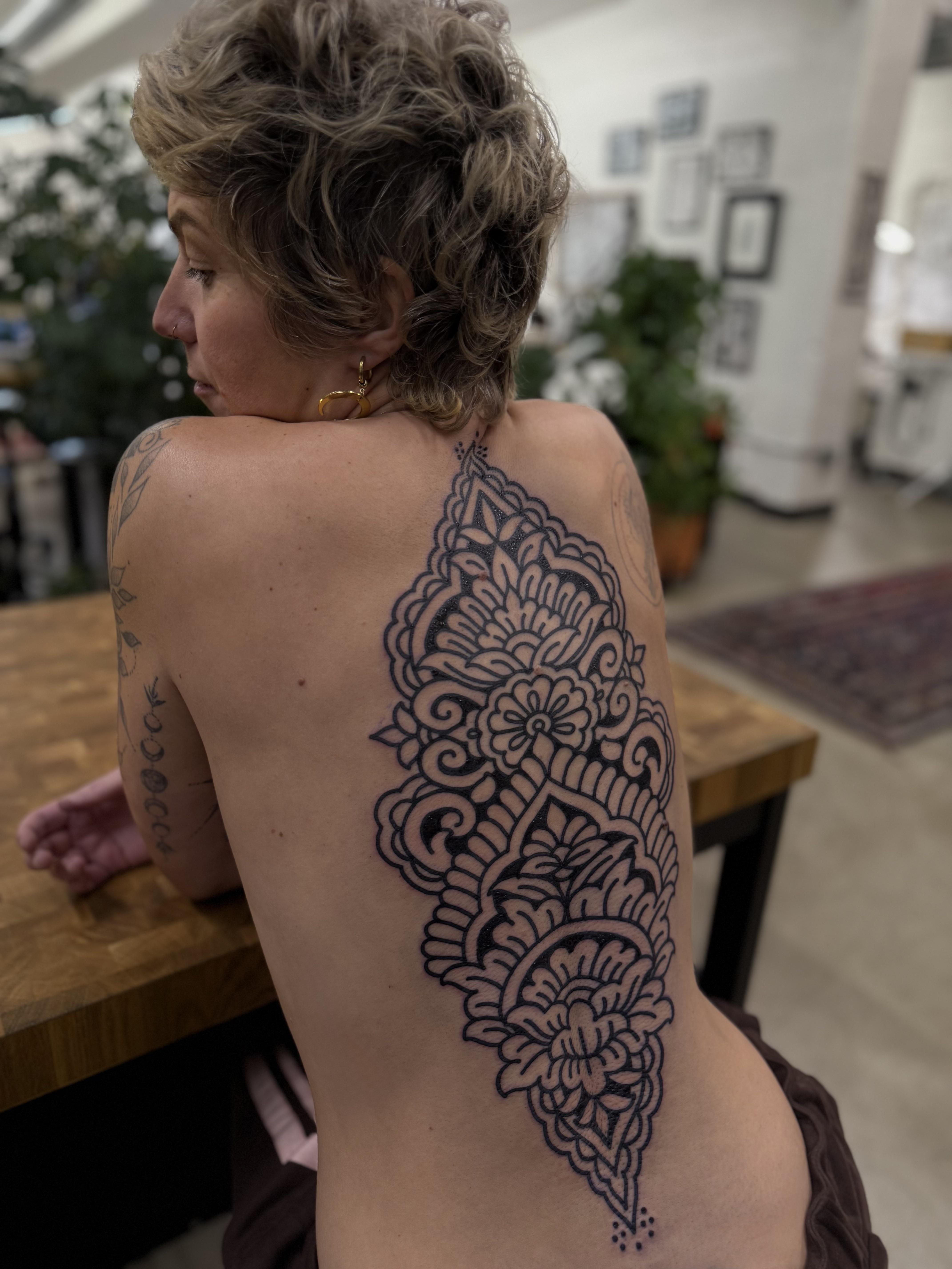 Intricate blackwork floral lace cascades along the spine.