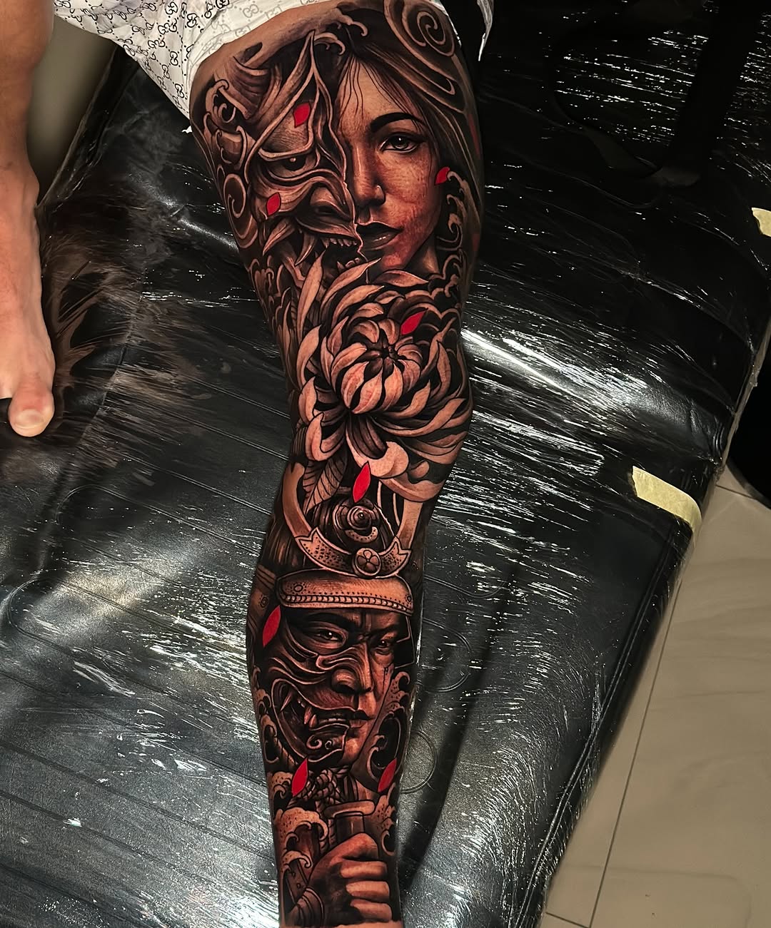 Dramatic black-and-gray full-leg sleeve with faces and florals.
