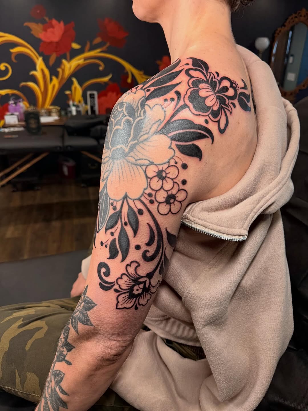 Bold blackwork floral details across shoulder and upper arm.