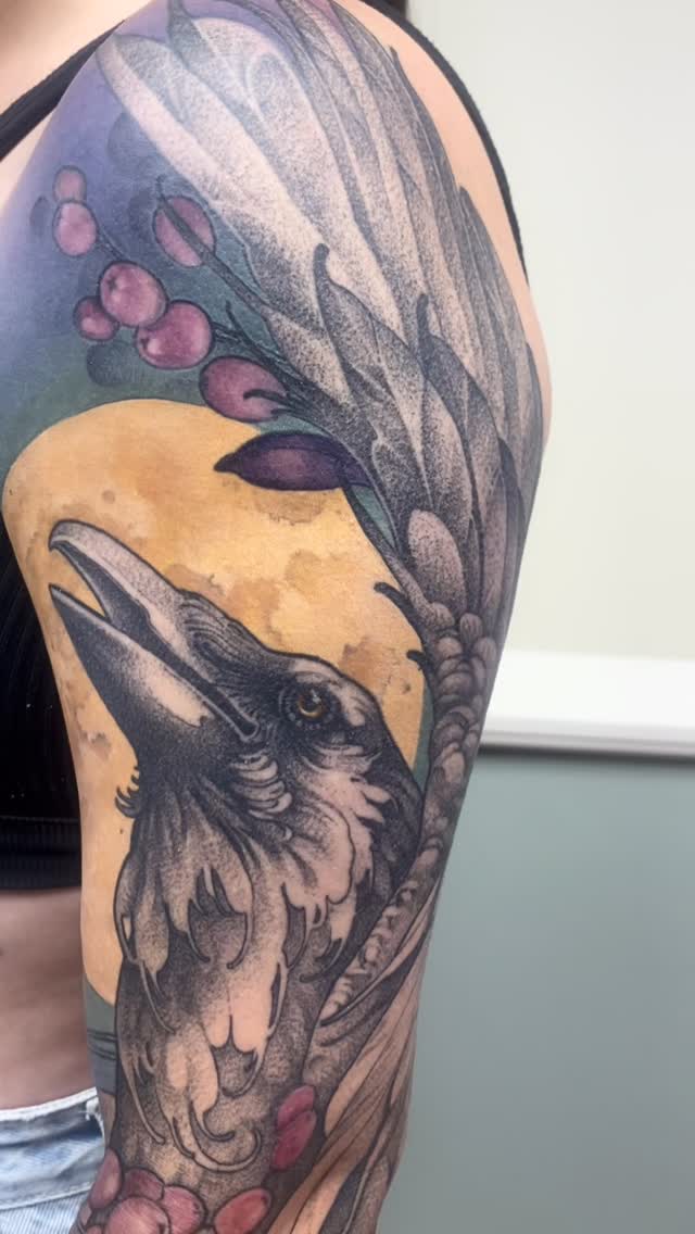 Raven and moon over pastel florals on arm.