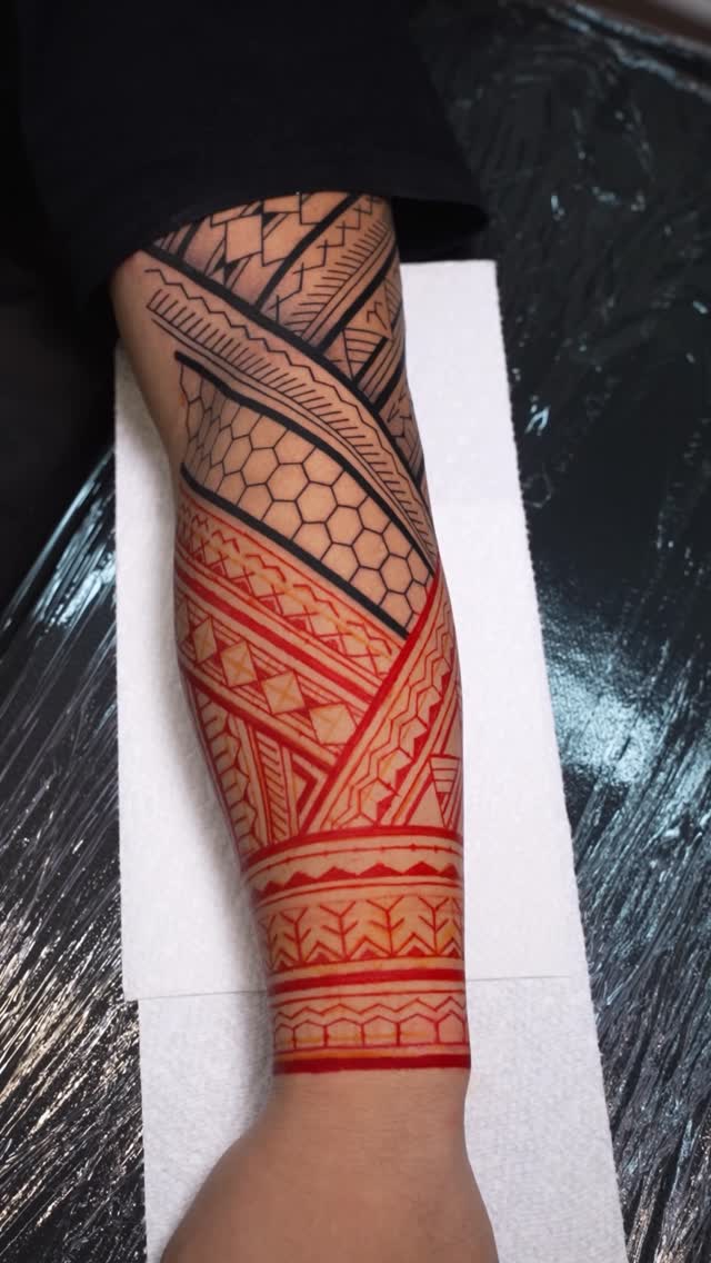 Intricate geometric tribal sleeve in bold black and red.