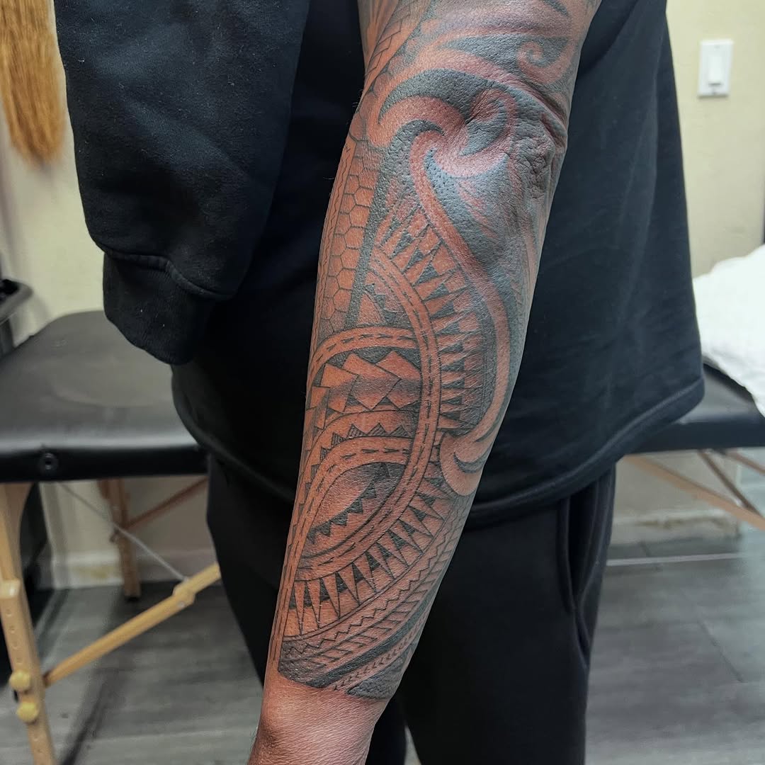 Intricate Polynesian tribal forearm tattoo with bold geometric bands.