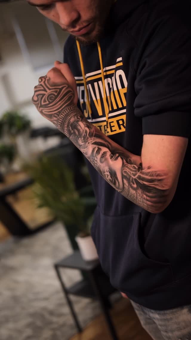 Intricate grayscale forearm sleeve with portrait and patterns.