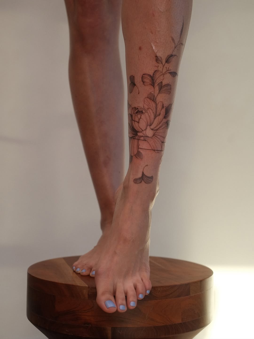 Delicate floral leg tattoo with fine-line petals