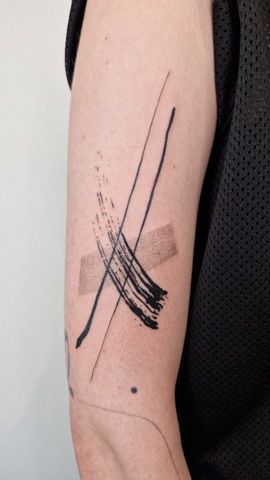 Minimalist abstract brush strokes crossing on forearm