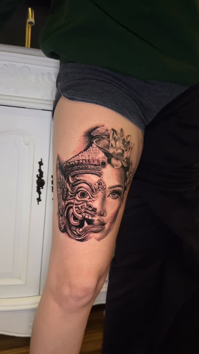 Intricate half-mask fused with floral portrait on thigh.