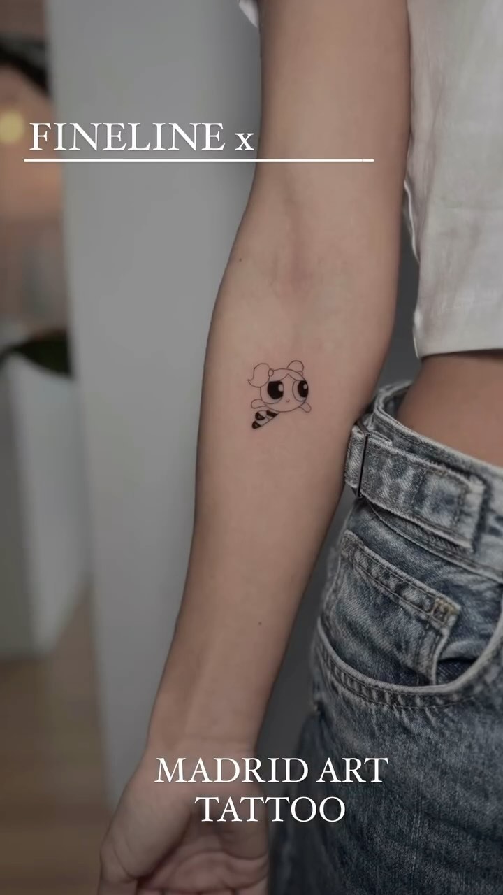 Delicate fine-line cartoon puppy on inner forearm.