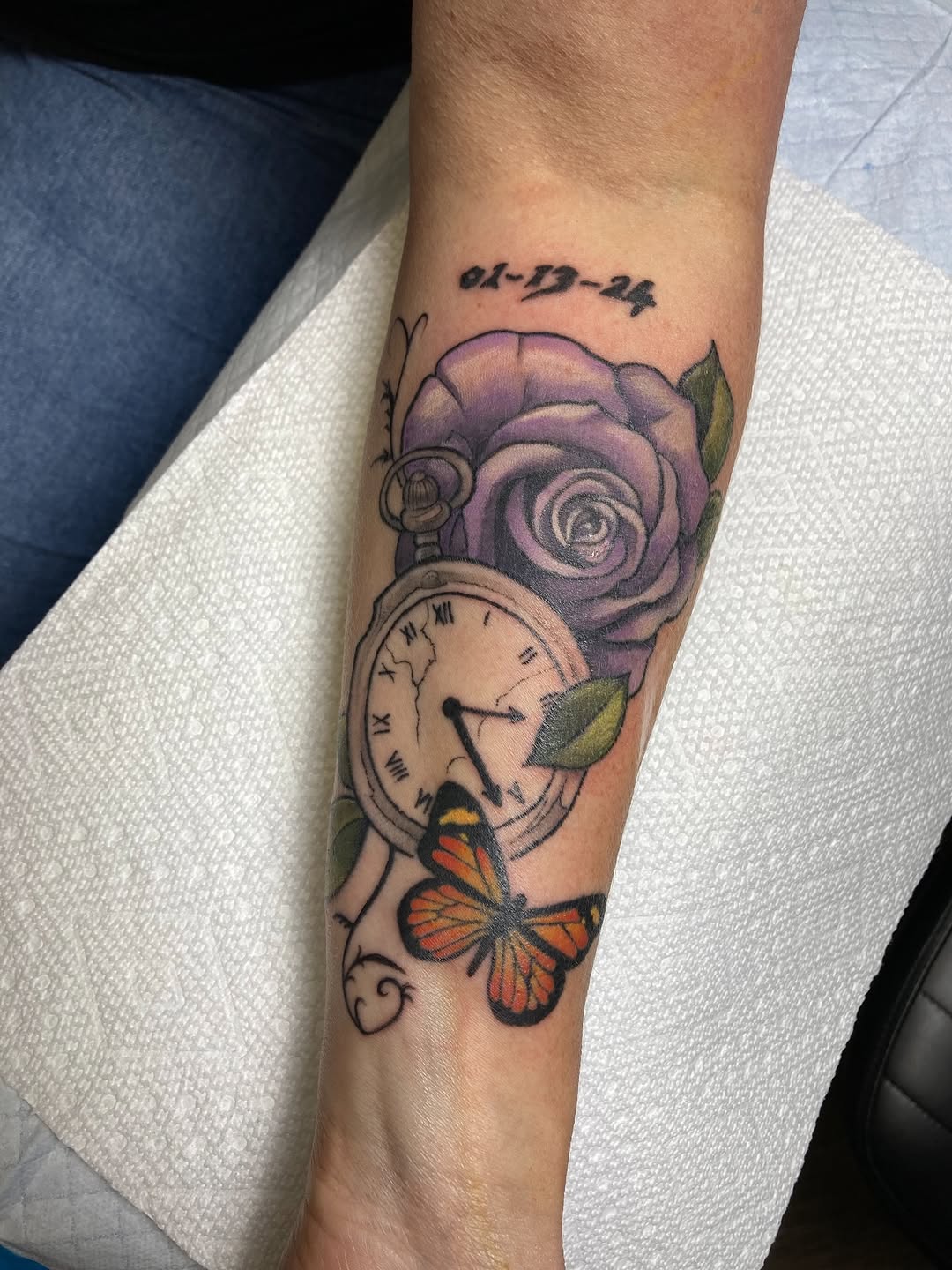 Vibrant memorial tattoo: purple rose, cracked clock, butterfly