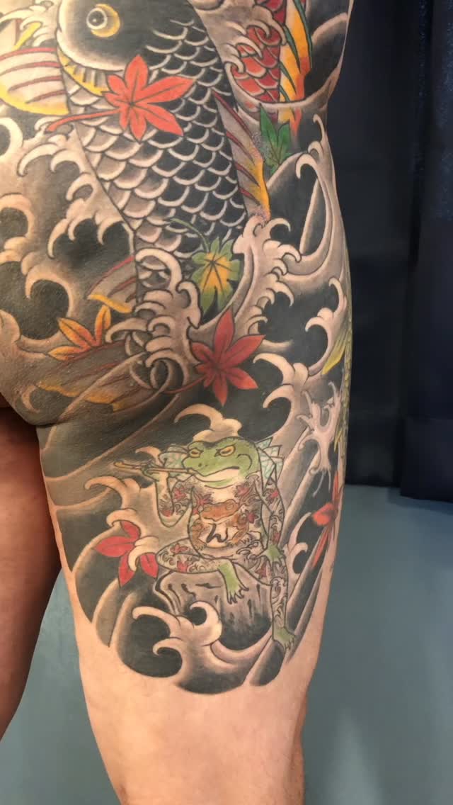 Vibrant Japanese koi tattoo with bold waves and maple leaves