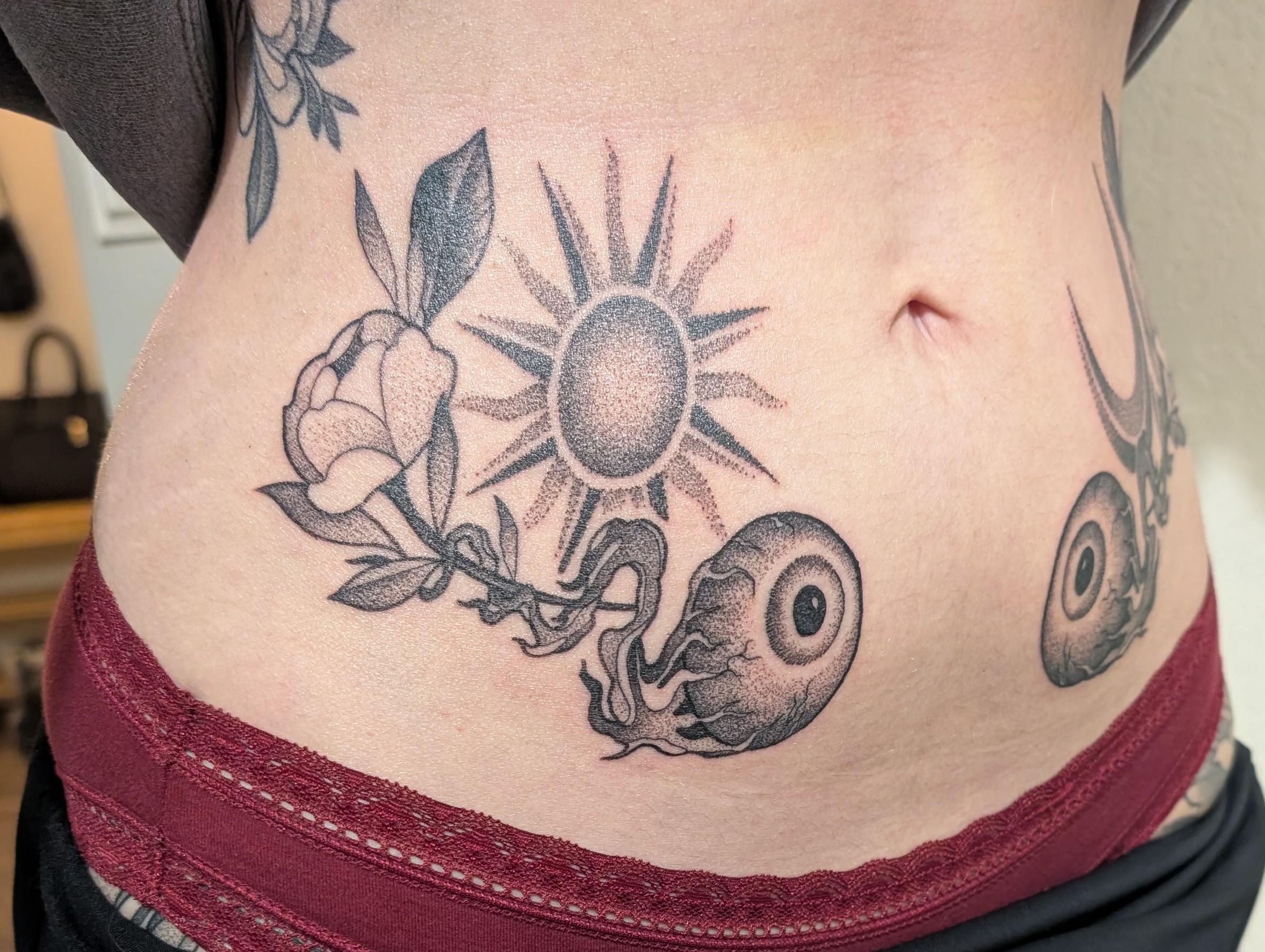 Bold blackwork sun, rose, and spiral shell on flank