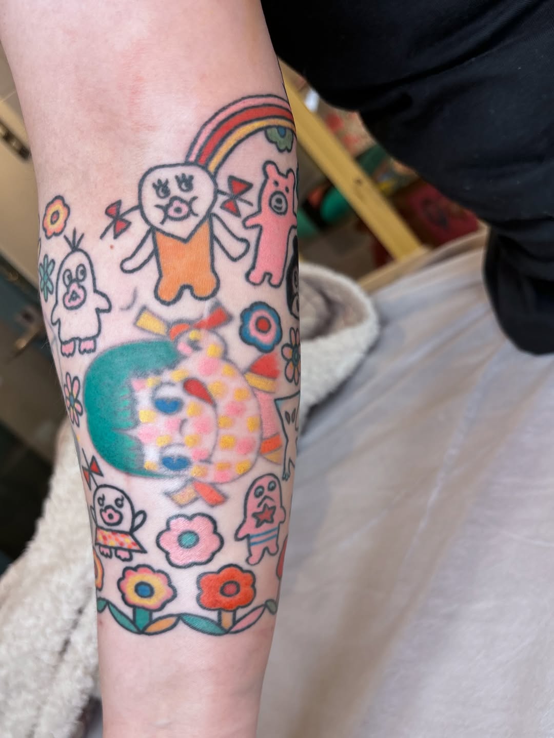 Bright kawaii-style cartoon characters form a playful forearm collage.