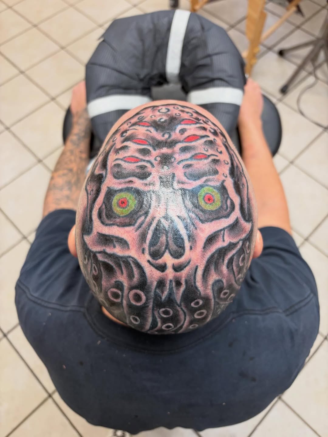 Cthulhu-inspired head tattoo with tentacled horror and red eyes.