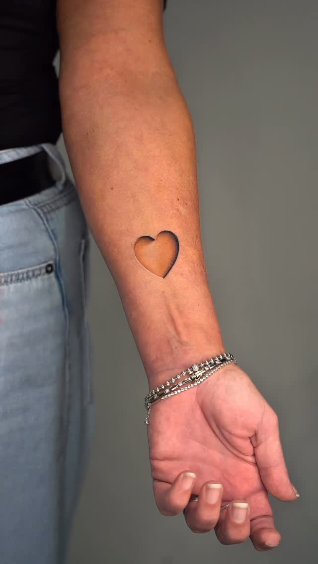 Negative-space heart on forearm with crisp outline
