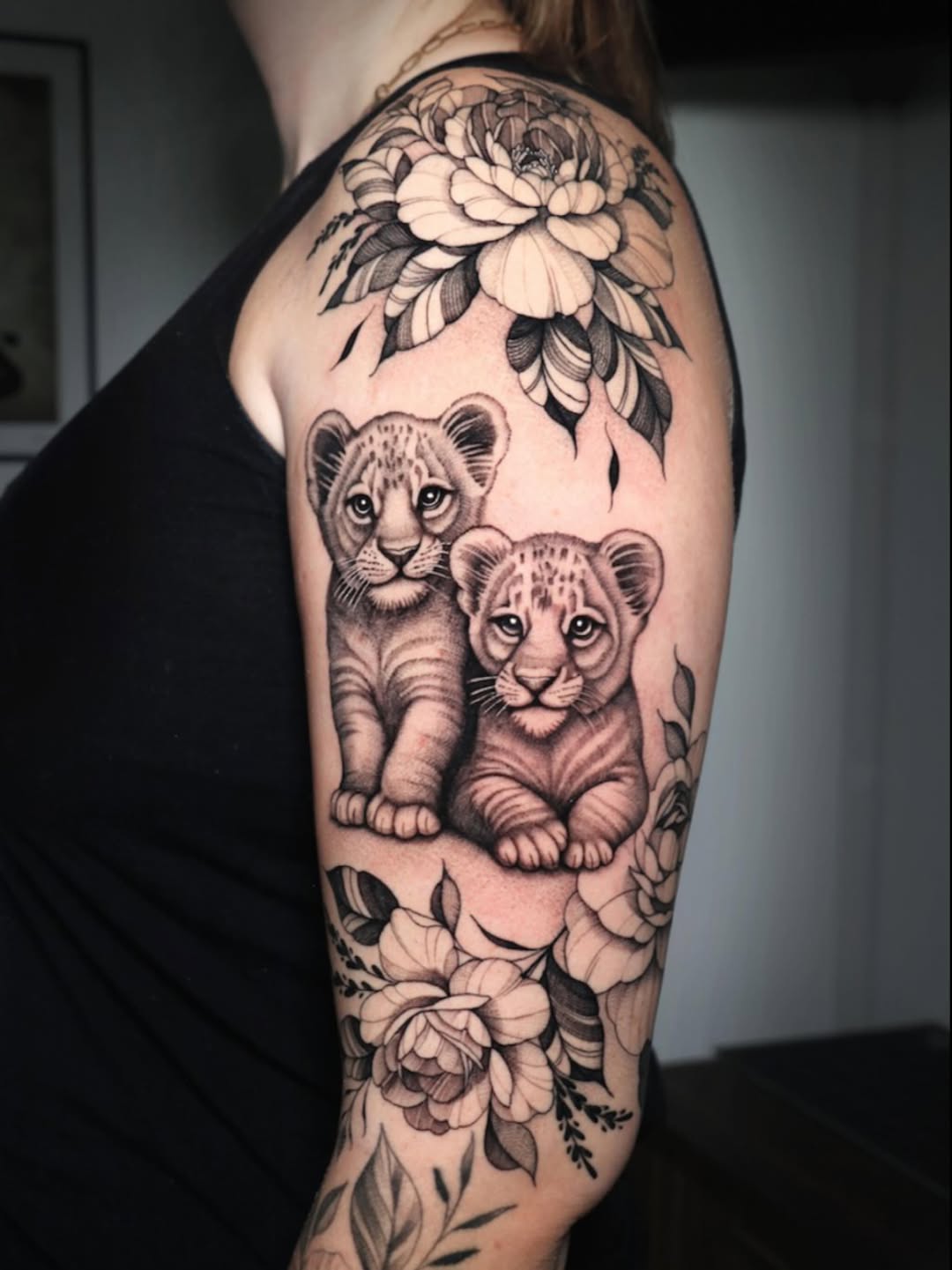 Two lion cubs among bold floral sleeve with shading