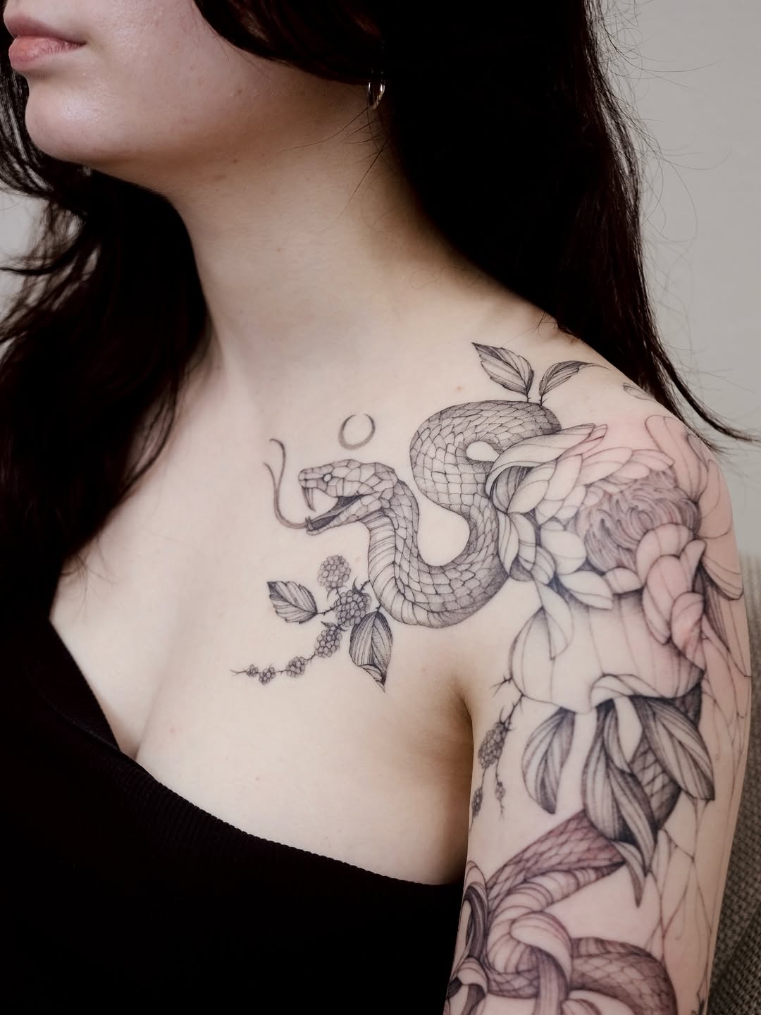 Intricate fineline snake weaving through blossoms and leaves.