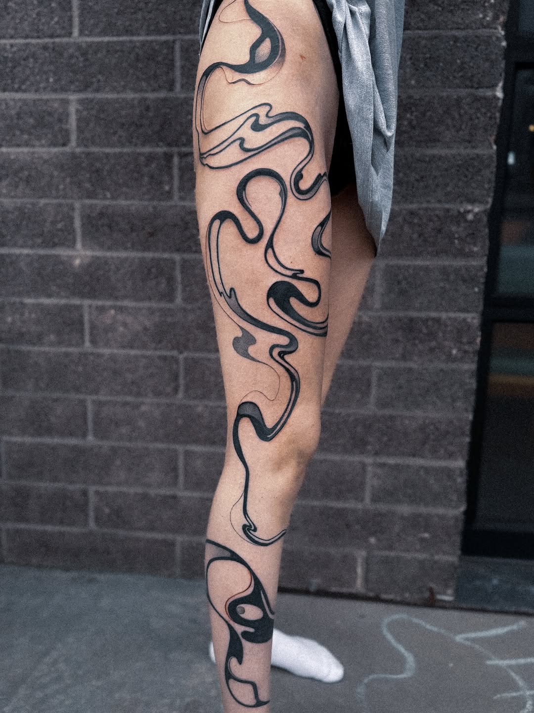 Bold flowing black acid-spill style linework down leg