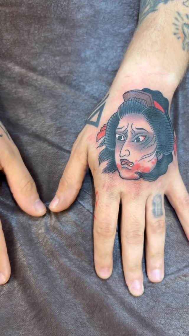 Bold geisha portrait on hand with red accents