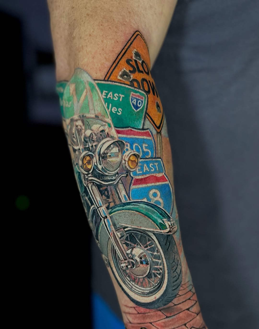 Vibrant motorcycle tattoo with highway signs, retro vibe